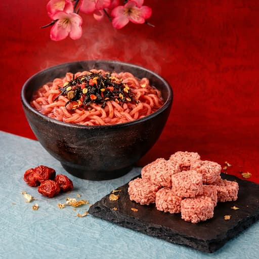 梅風味をイメージしたピンク系カラーのスナックビジュアル。丸いひとくちサイズのスナックと梅モチーフを組み合わせた、春らしく爽やかなイメージ画像。