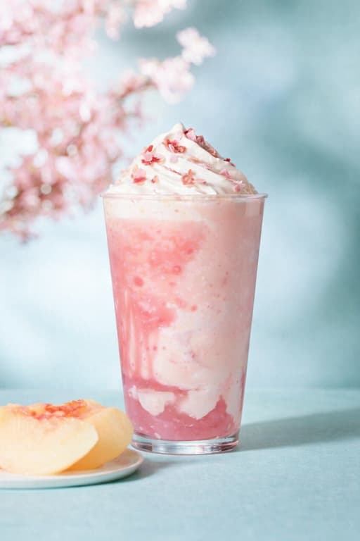 桜の花を背景にしたピンクとホワイトの層がある春限定ドリンクのイメージ画像。2026年2月18日発売のSAKURAビバレッジを紹介するシンプルな写真。