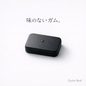 白い背景に置かれたマットブラックの缶ケース。中央に小さな赤いドットがあり、「味のないガム」という静かなコンセプトを表現したイメージ画像。